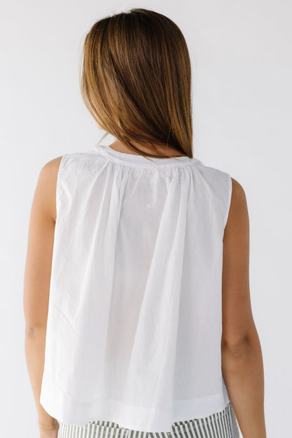 Back view of a woman wearing a loose fitting white sleeveless blouse.