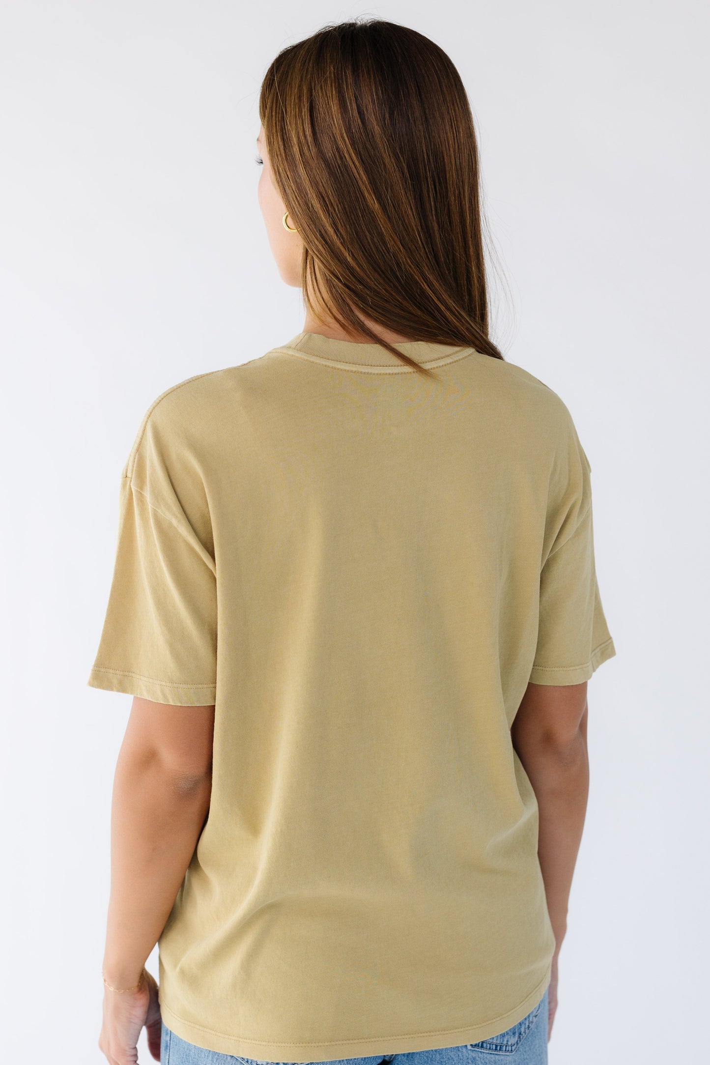 Back view of a woman wearing a light mustard tee.