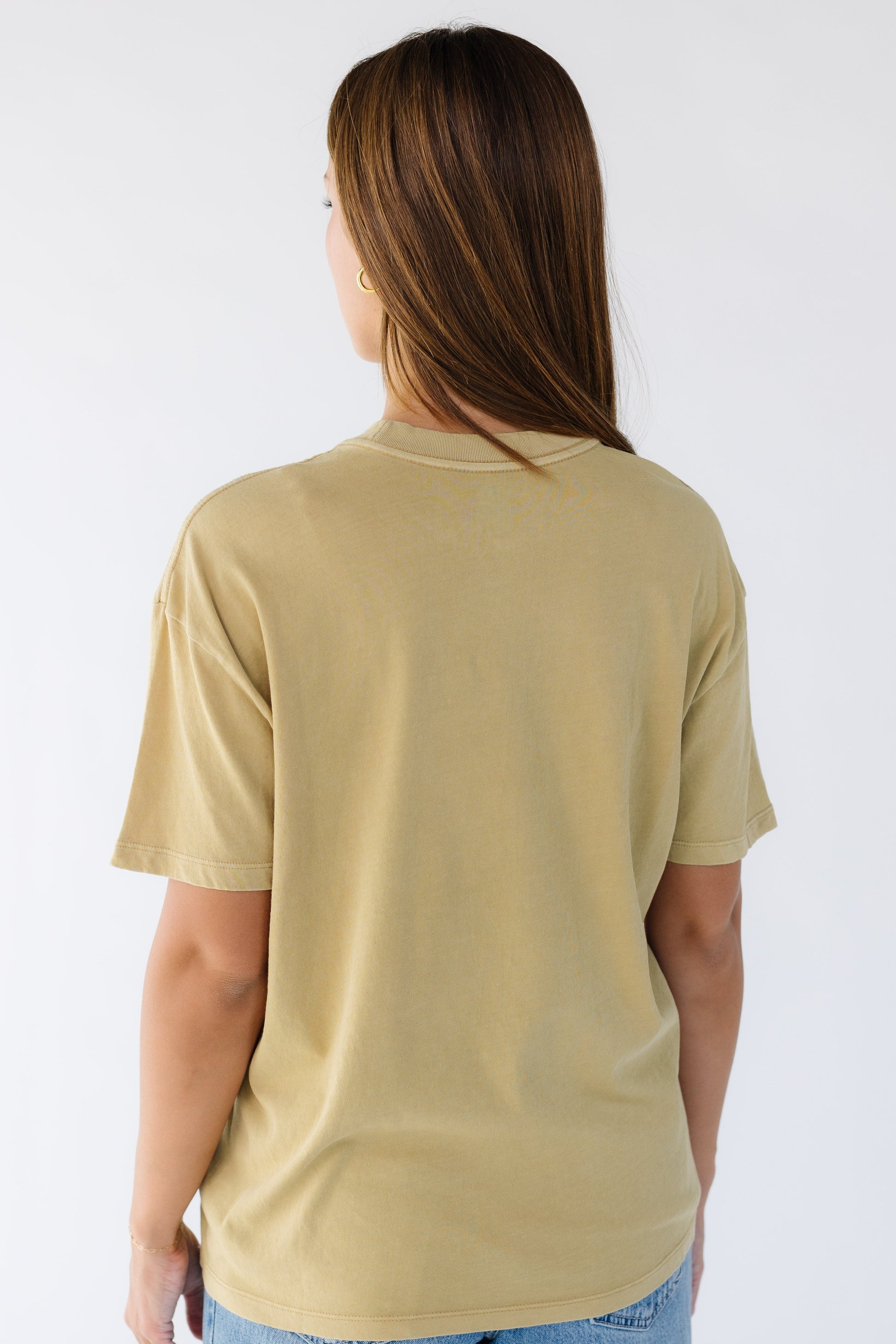 Back view of a woman wearing a light mustard tee.