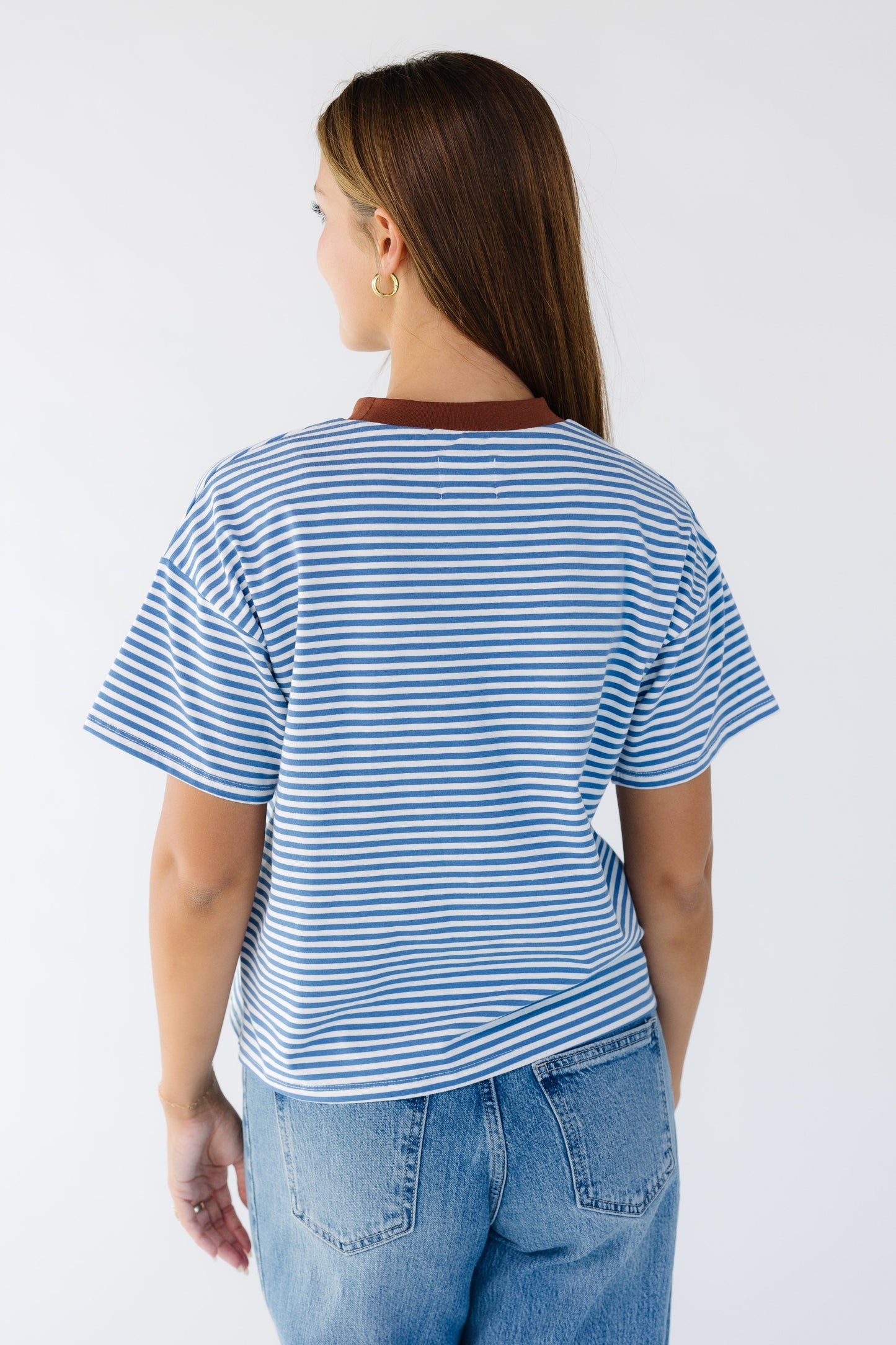 Back view of a young woman wearing a blue and white stripe tee with shot sleeves.