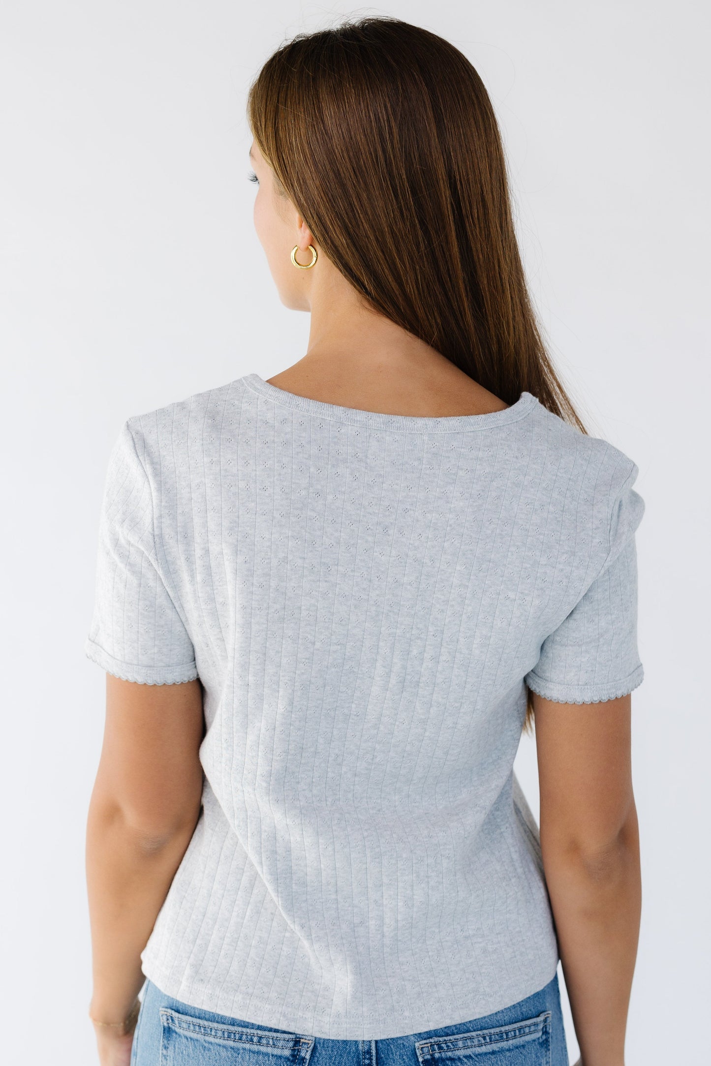 Back view of woman wearing a grey pointelle soft knit top with short sleeves.