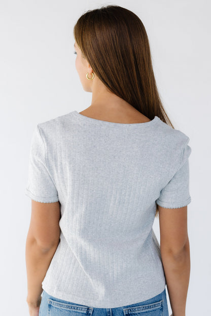 Back view of woman wearing a grey pointelle soft knit top with short sleeves.