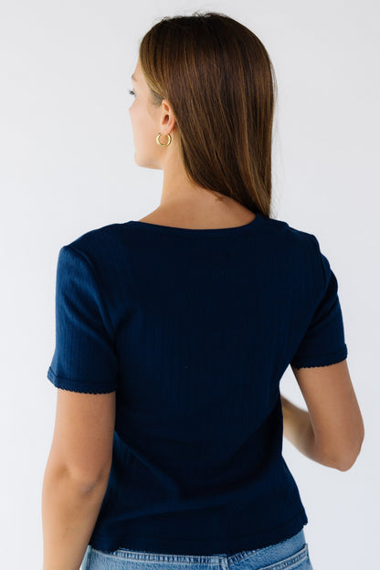 Back view of a woman wearing a navy knit short sleeve top.