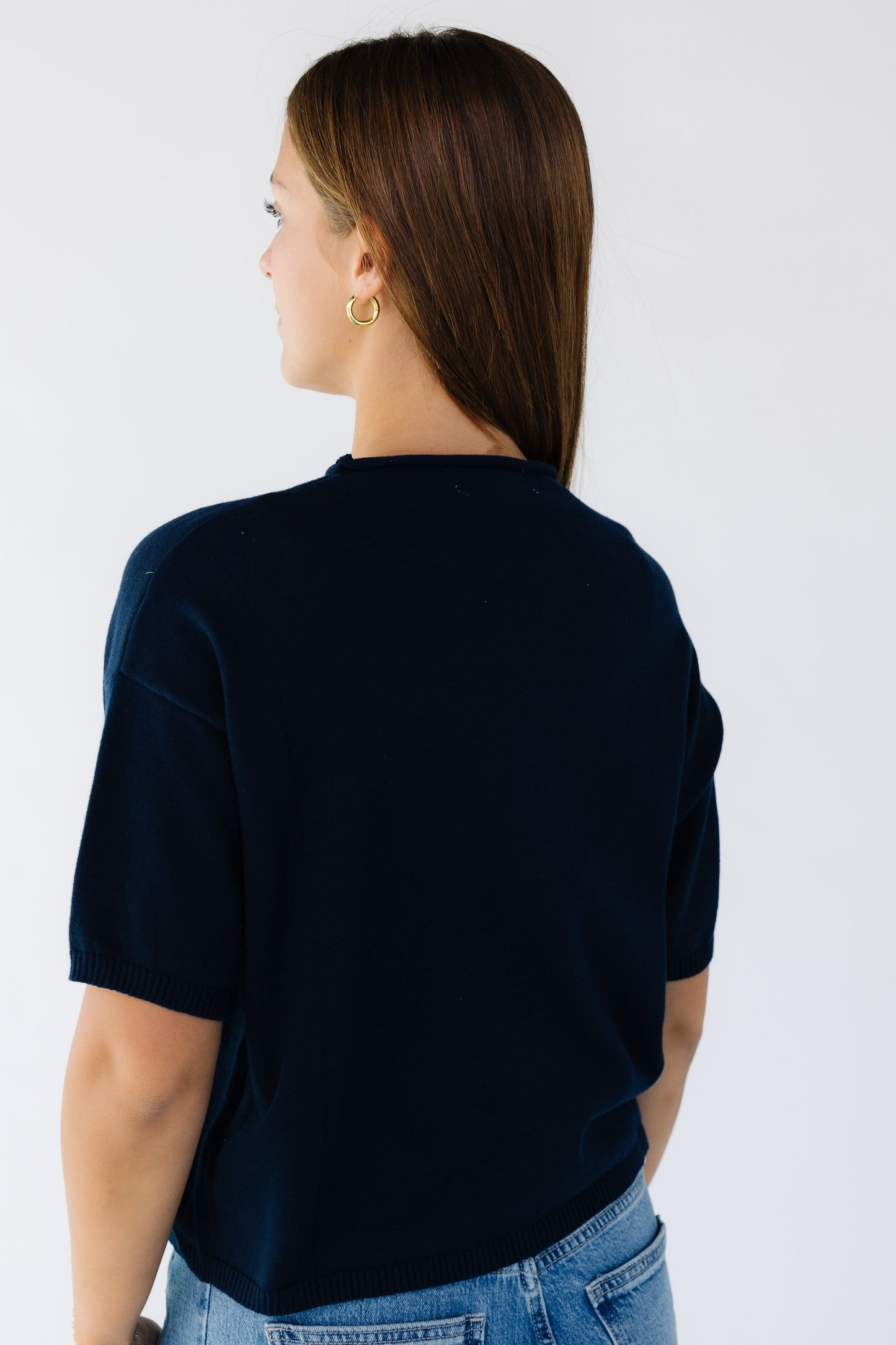 Back view of a woman wearing a navy short sleeve sweater.