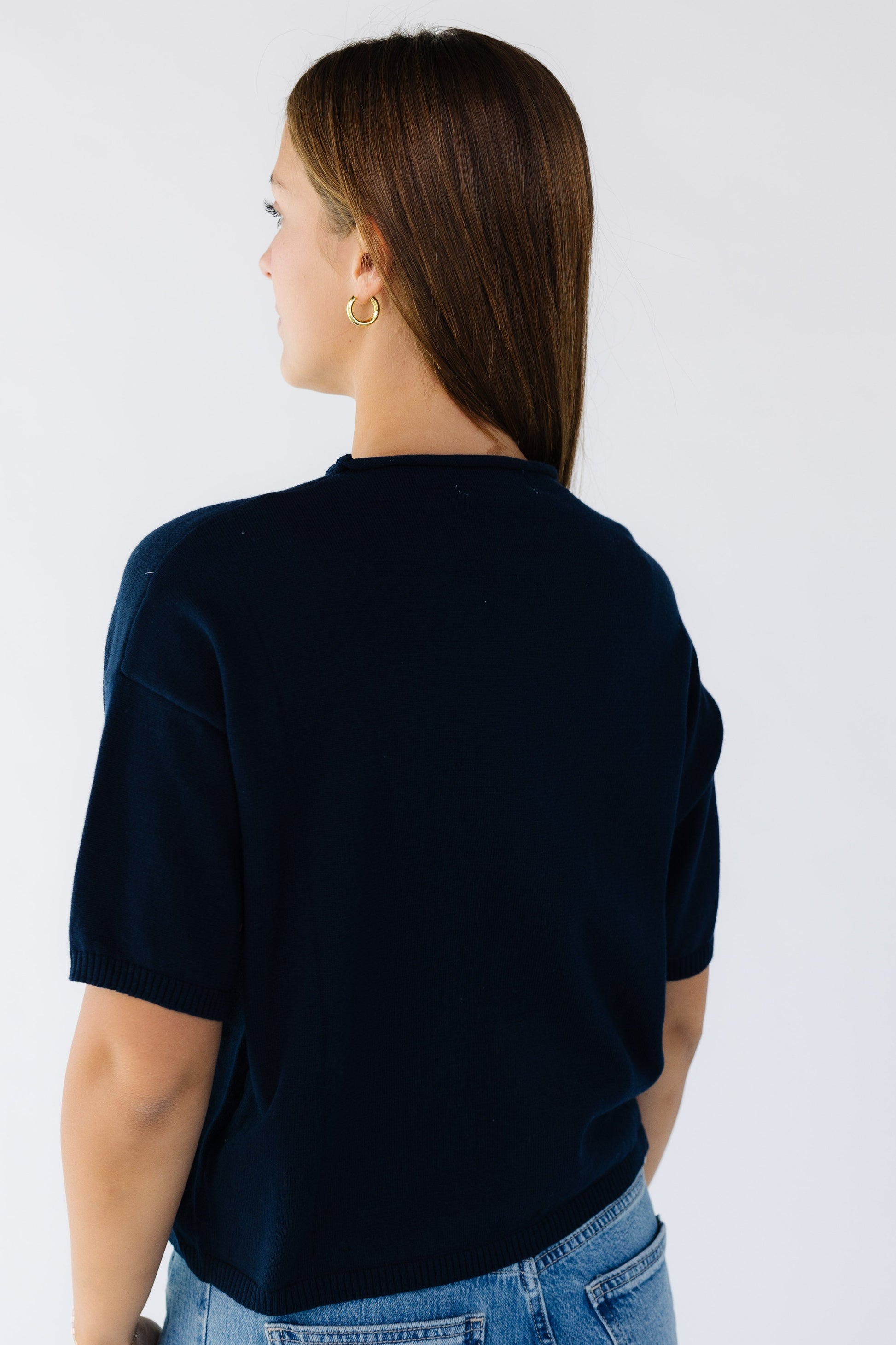 Back view of a woman wearing a navy short sleeve sweater.