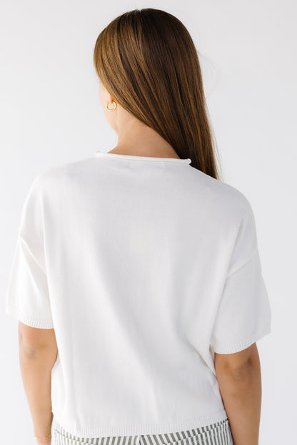 Back view of a woman wearing an ivory button down cardigan with short sleeves.