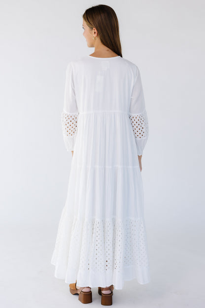 Back view of a woman wearing a white maxi with eyelet tiers and sleeve sections.