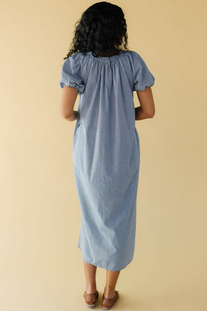 Back view of a woman wearing a navy & white gingham midi dress with balloon sleeves.