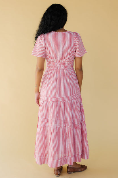 Back view of a young woman wearing a red & white stripe midi-maxi dress with short sleeves and a wide elastic waist.