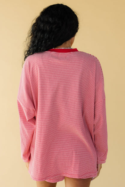 Back view of a woman wearing an oversized red & white stripe loose fitting top with long sleeves.