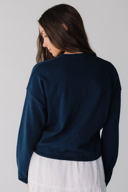 Back view of woman wearing long sleeve navy sweater