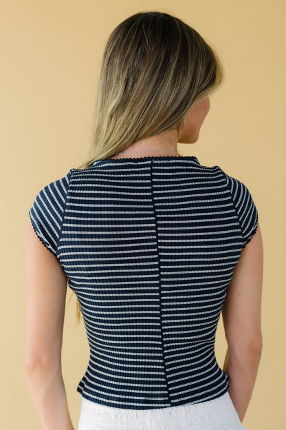 Back view of a woman wearing a navy stripe, close fitting stripe top with cap sleeves.