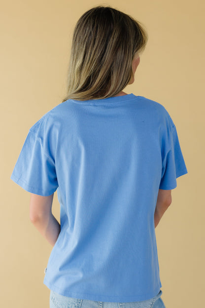 Back view of a young woman wearing a blue short sleeve tee.