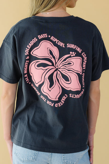 Back view of a young woman wearing a black graphic tee with a large back floral graphic.