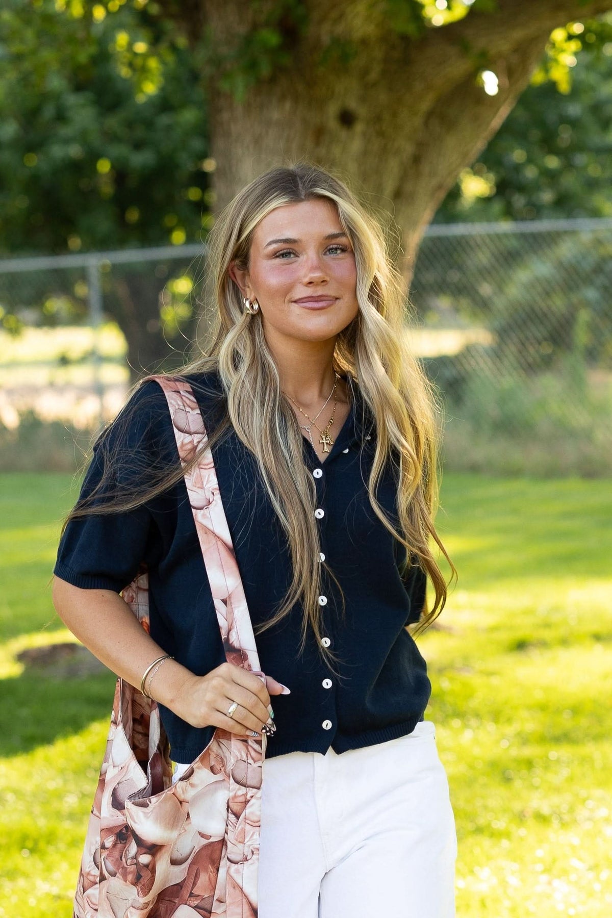 Young woman wearing a button down navy cardigan with short sleeves.
