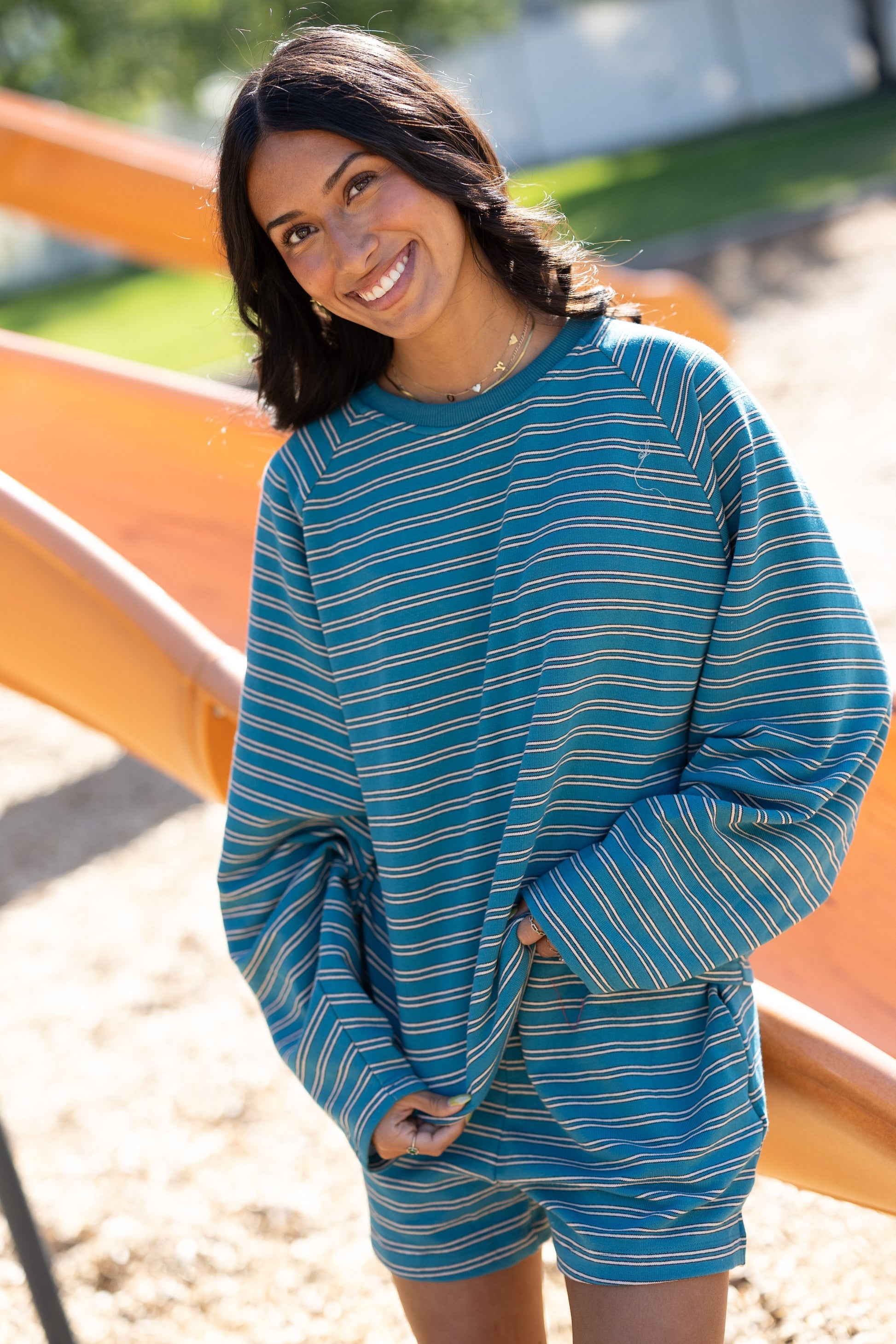 Young woman wearing a teal stripe short set with long sleeves and wide leg shorts.