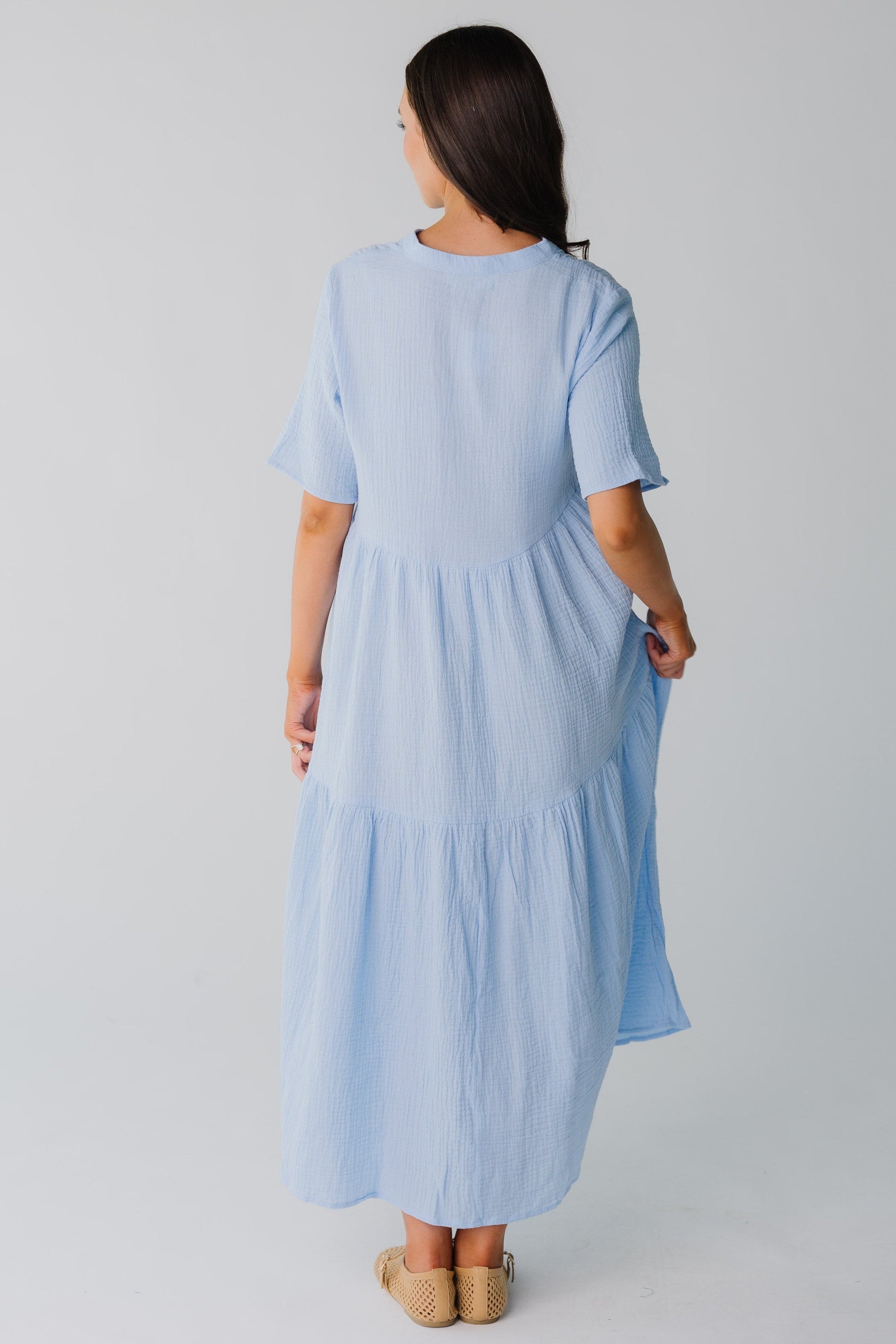 Back view of women's light blue midi dress with wide bottom ruffle and short sleeves