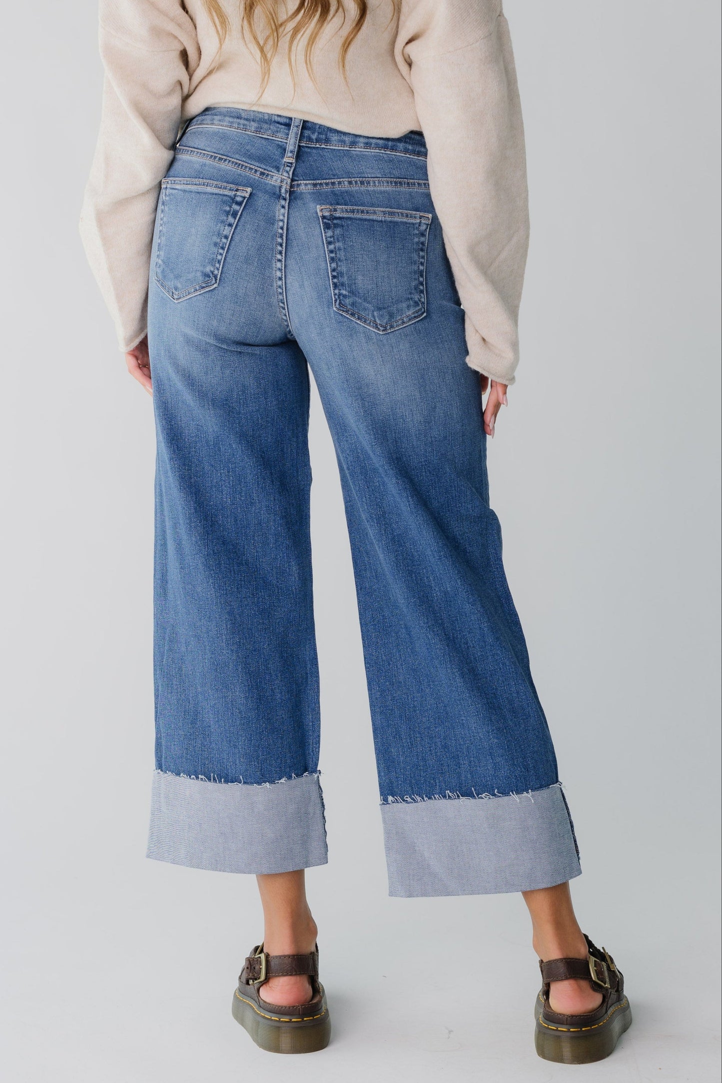 Back view of medium denim wide leg jeans with wide bottom cuff