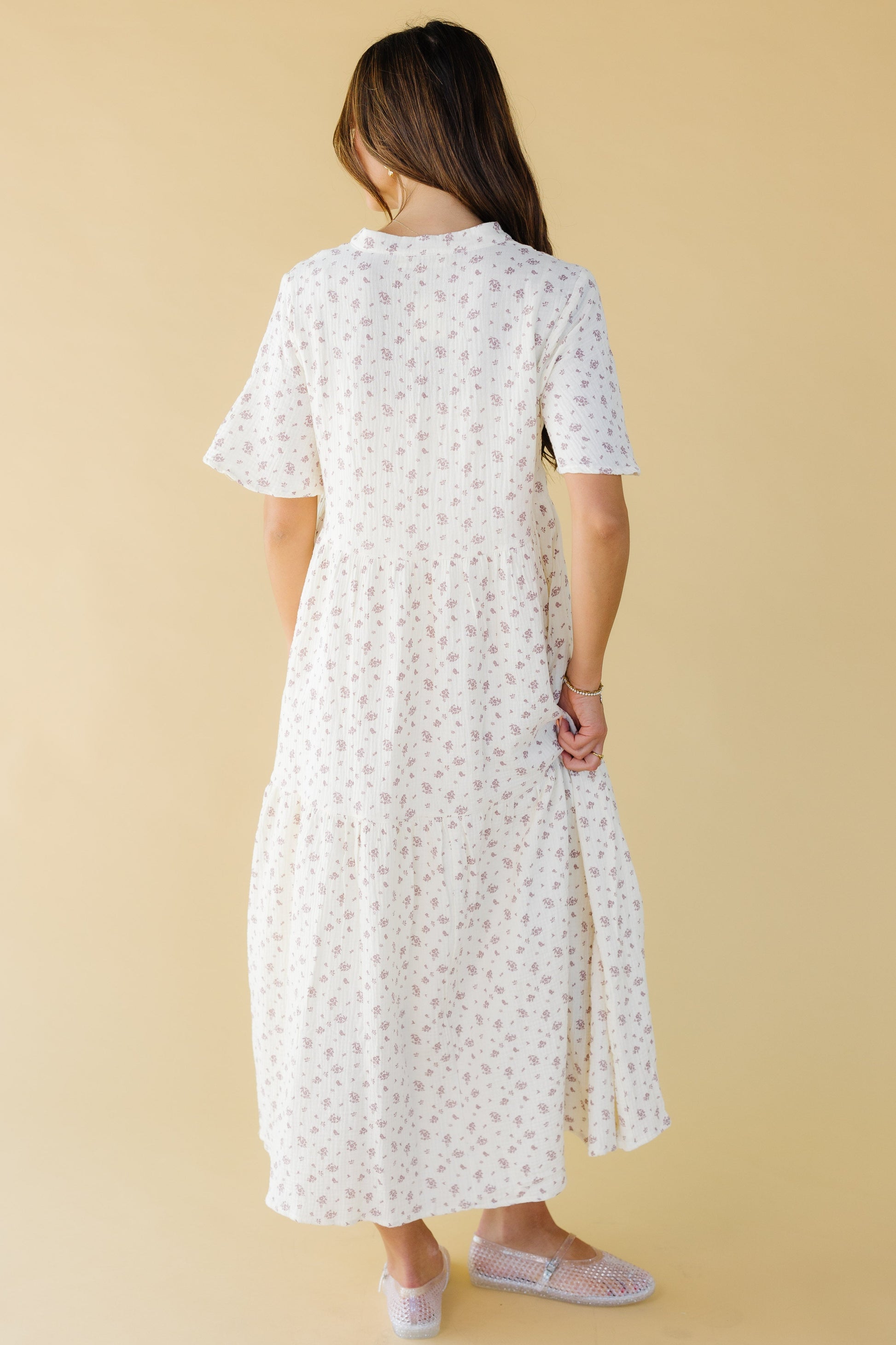 Back view of a woman wearing a cream & mauve floral print midi-maxi with short sleeves.