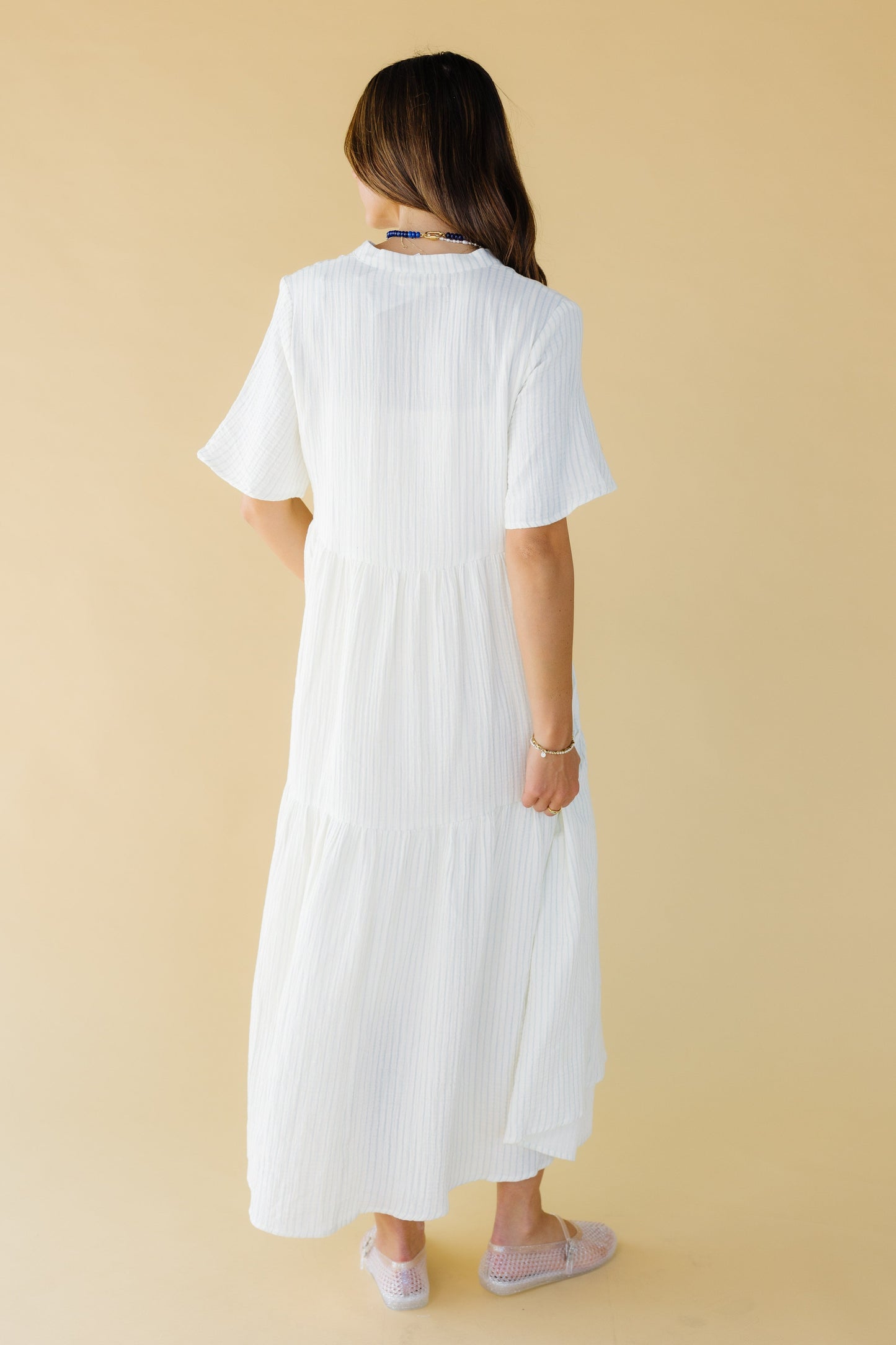 Back view of a woman wearing a white & light blue stripes with elbow length sleeves.