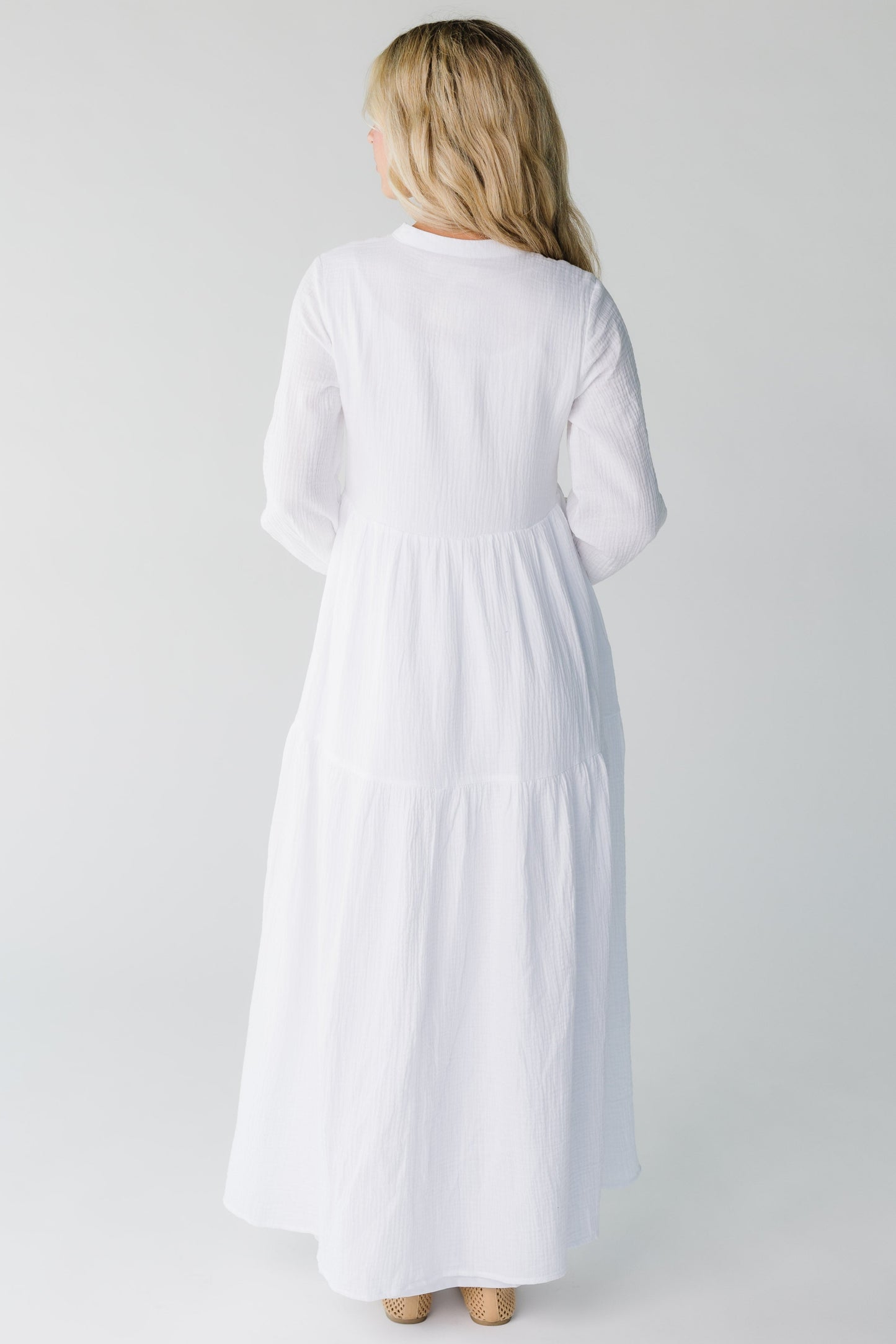 Back view of women's white maxi dress with long sleeves
