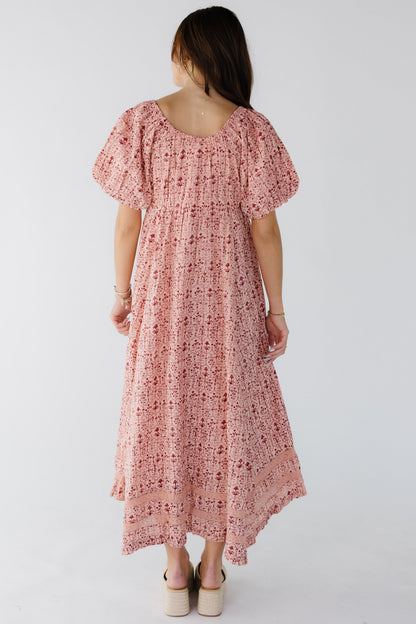 Back view of a woman wearin a pink print midi-maxi dress with a kercheif-ruffle hem with lace insets and balloon sleeves.
