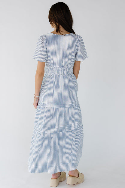 Back view of a young woman wearing a white and blue stripe with short sleeves.