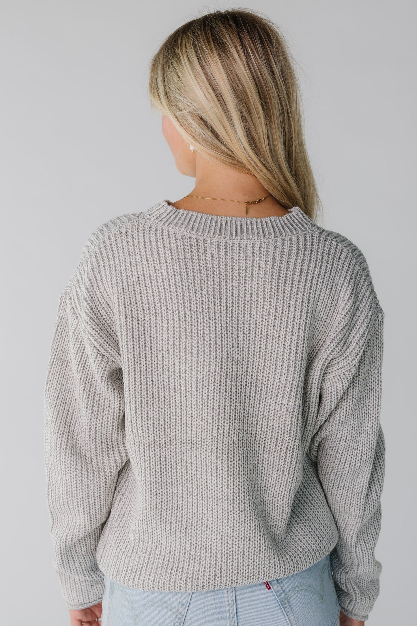 Back view of a woman wearing a light grey loose fitting sweater