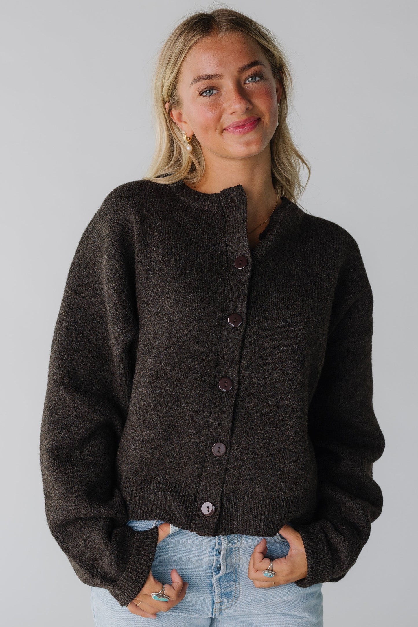 A woman wearing a  dark brown button cardigan with long sleeves