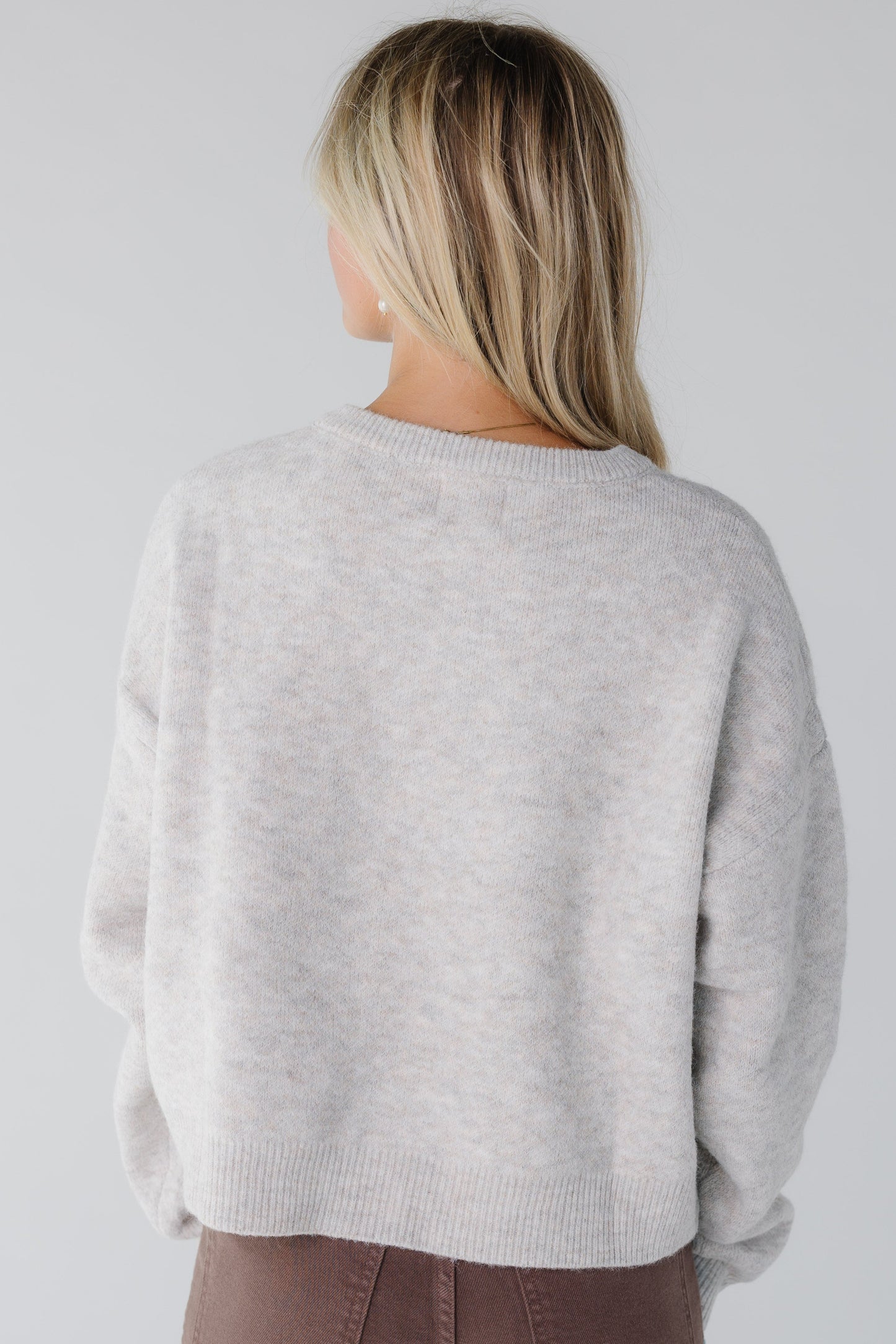 Back view of a woman wearing a  heather oat long sleeve cardigan