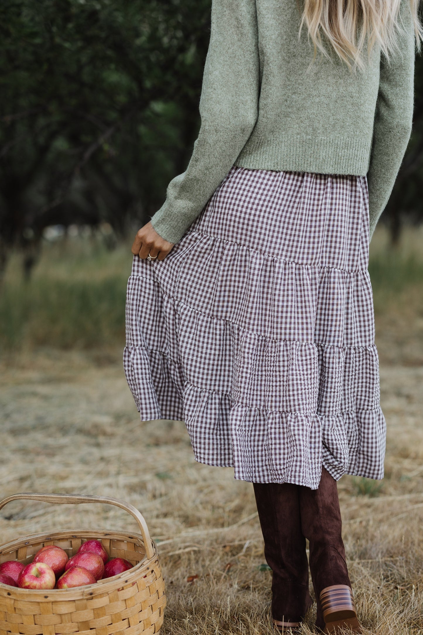 Back view of a woman wearing a brown & white gingham tiered midi skirt with an elastic waistband.