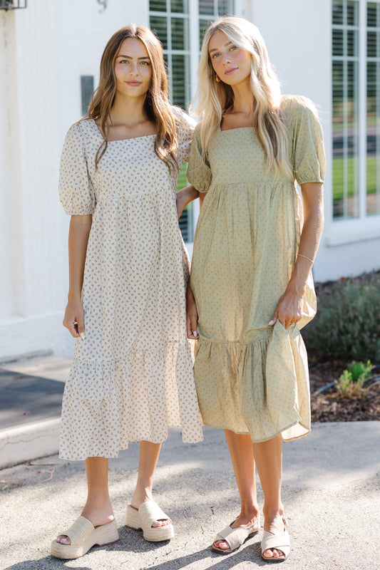 Two young women wearing matching modest midi dresses in cream and ivory.