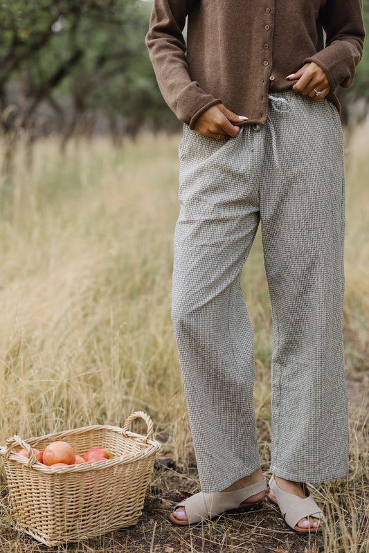 Young woman wearing a modest pair of loose fitting gingham ants with an elastic & waist tie belt.