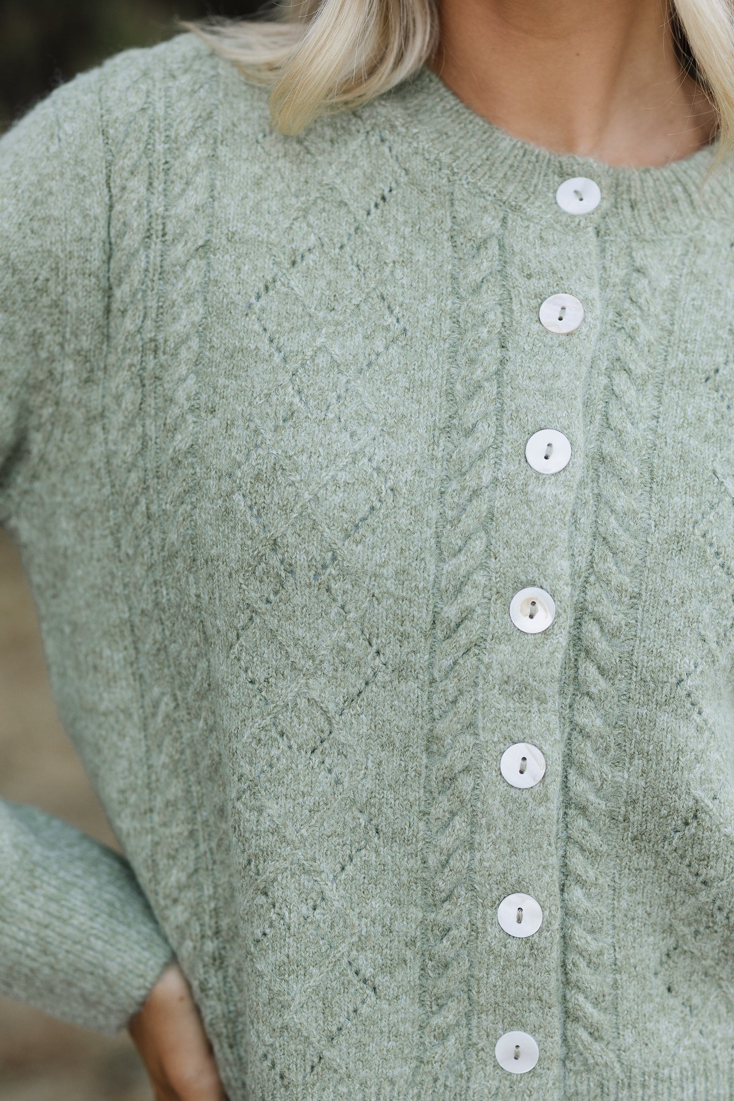 Close view of a cable and patterned knit button down cardigan.