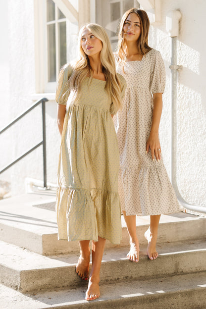 Women wearing print midi dresses with square necklines, large puff sleeves and bottom ruffles.