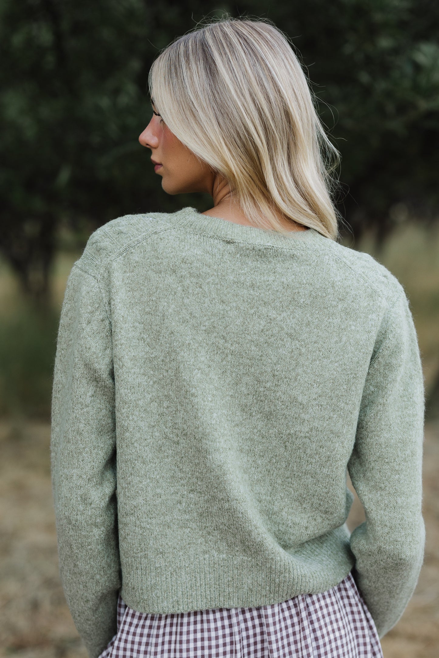 Back view of a woman wearing a green long sleeve sweater.