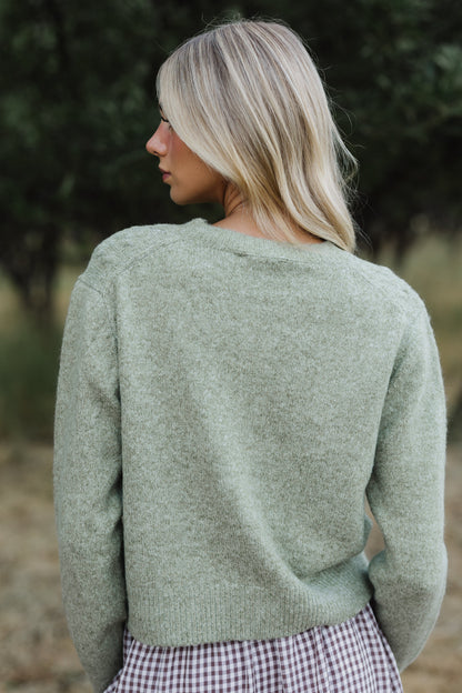 Back view of a woman wearing a green long sleeve sweater.