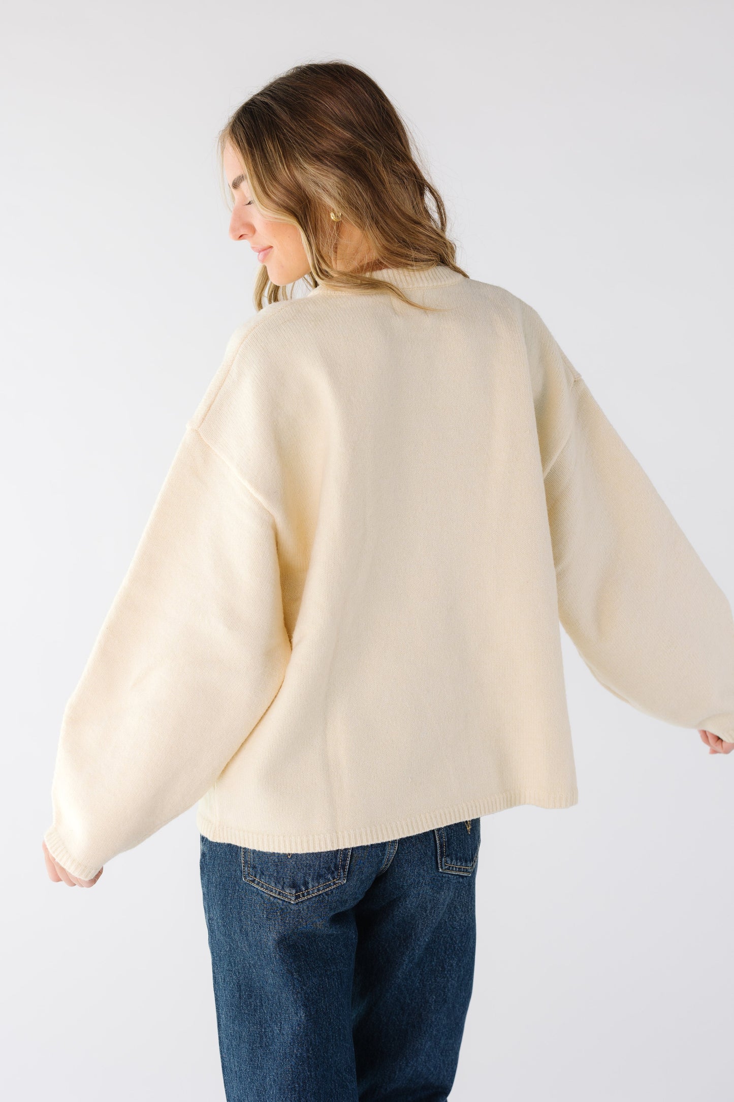 Back view of a woman wearing a loose fitting cream cardigan