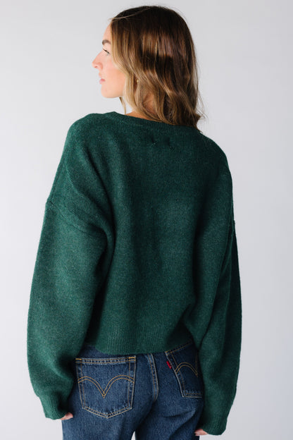 Back view of a woman wearing a dark green cardigan with long sleeves