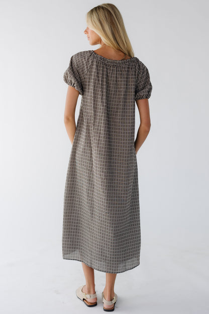 Back view of a woman wearing a black plaid midi dress with puff sleeves.