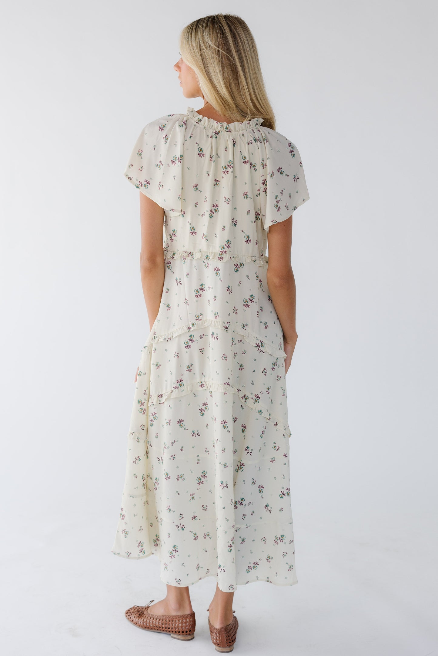 Back view of a woman wearing a cream & lavender floral print midi dress.