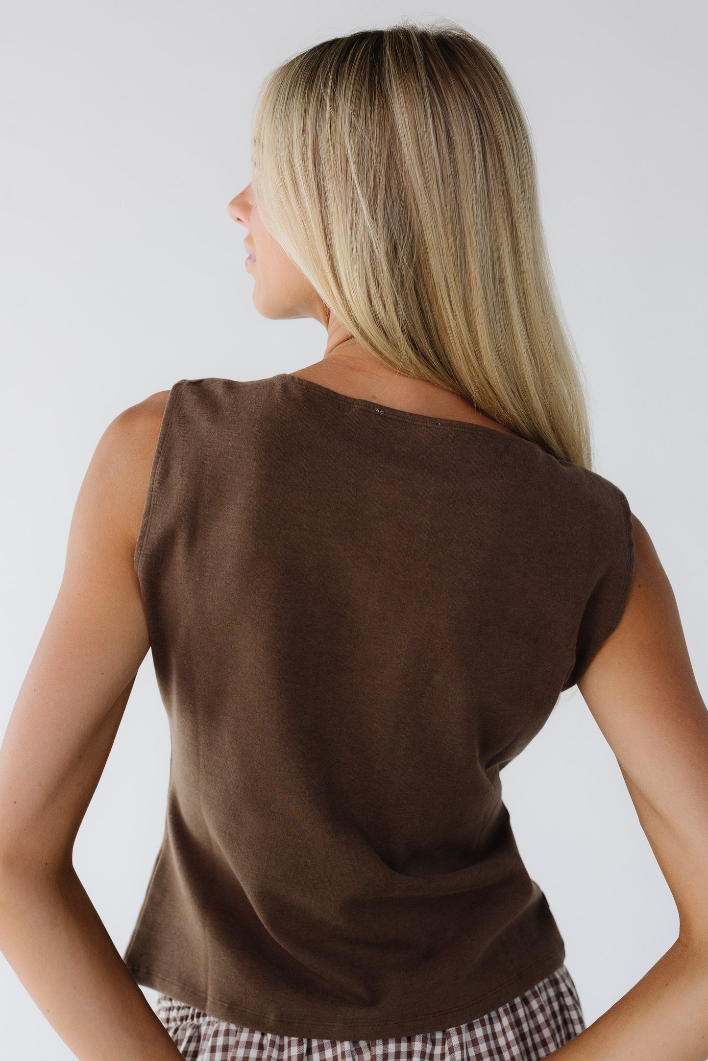 Back view of a woman wearing a sleeveless brown close fitting top.