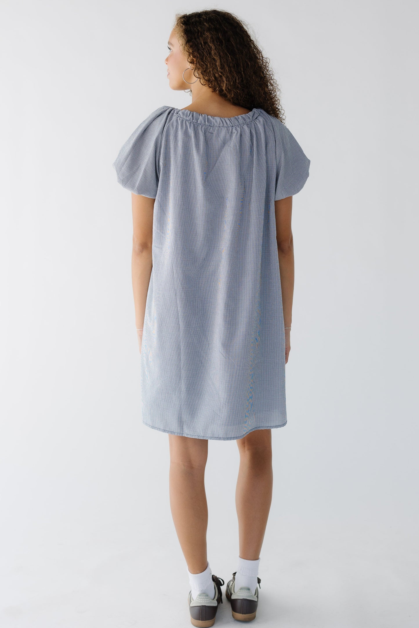 Back view of a woman wearing a navy & white short dress with balloon sleeves.