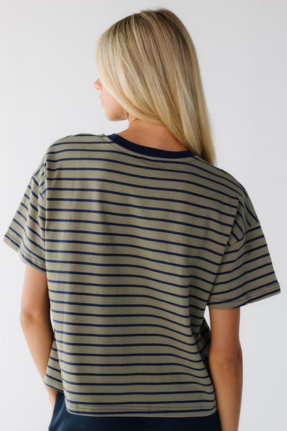 Back view of a woman weariang a olive and navy stirpe loose fitting tee with short sleeves.