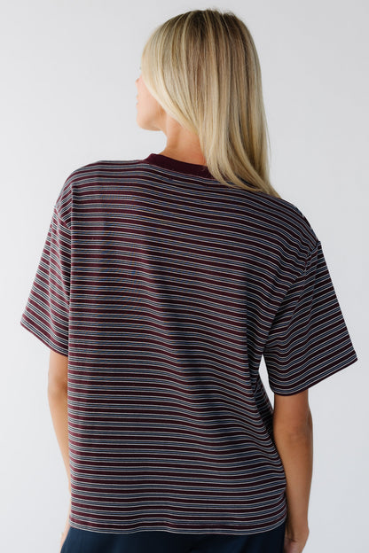 Back view of a woman wearing an oversized short sleeve tee in burgundy and grey stripe.
