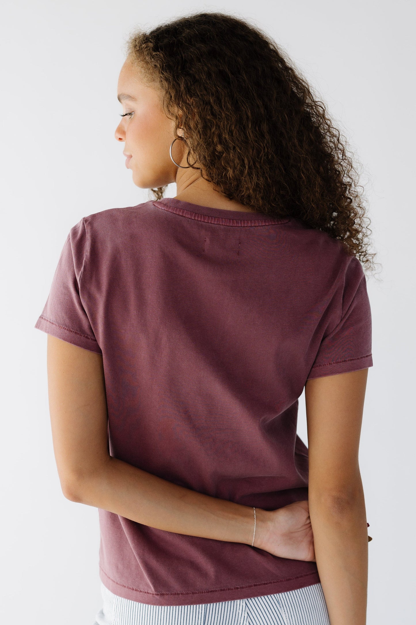 Back veiw of a woman wearing a wine color short sleeve tee.