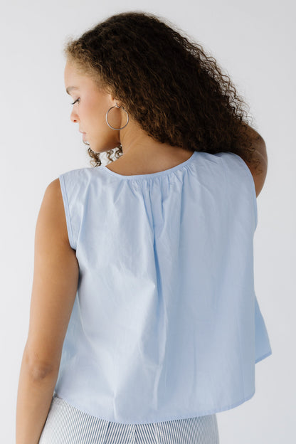 Back view of a woman wearing a loose fitting sleeveless in light blue.