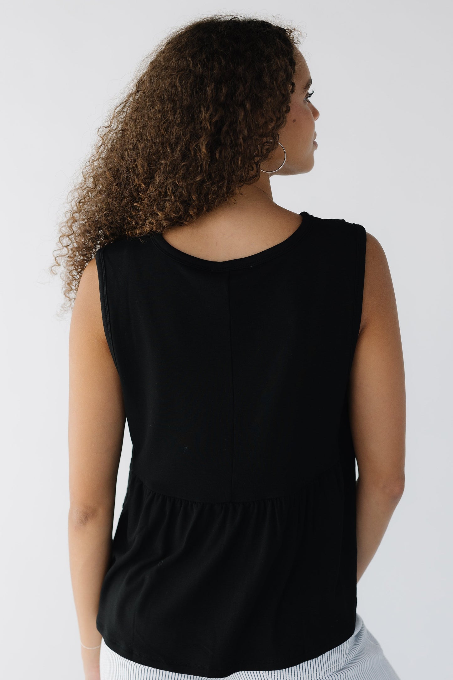 Back view of a woman wearing a black leeveless knit top.