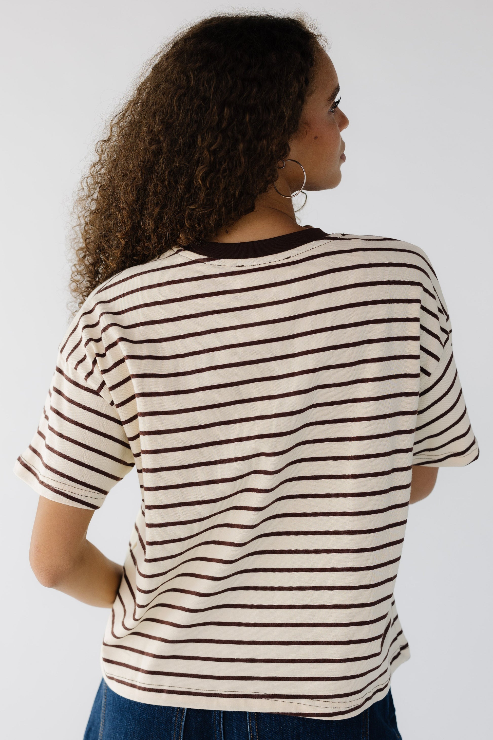 Back view of a teenage girl wearing a cream and brown stripe short sleeve tee.