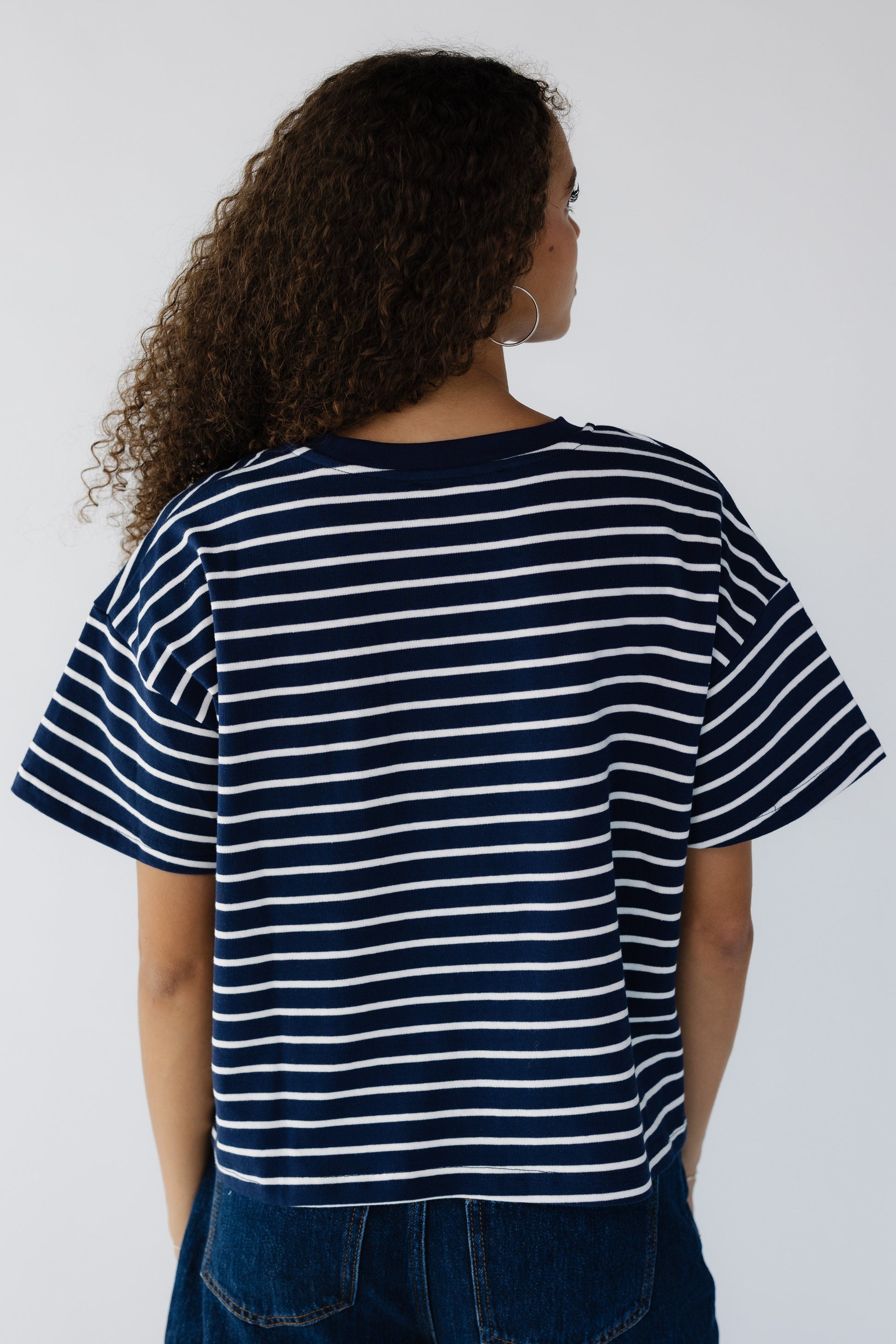 Back view of a woman wearing a navy & white stripe short sleeve tee. 